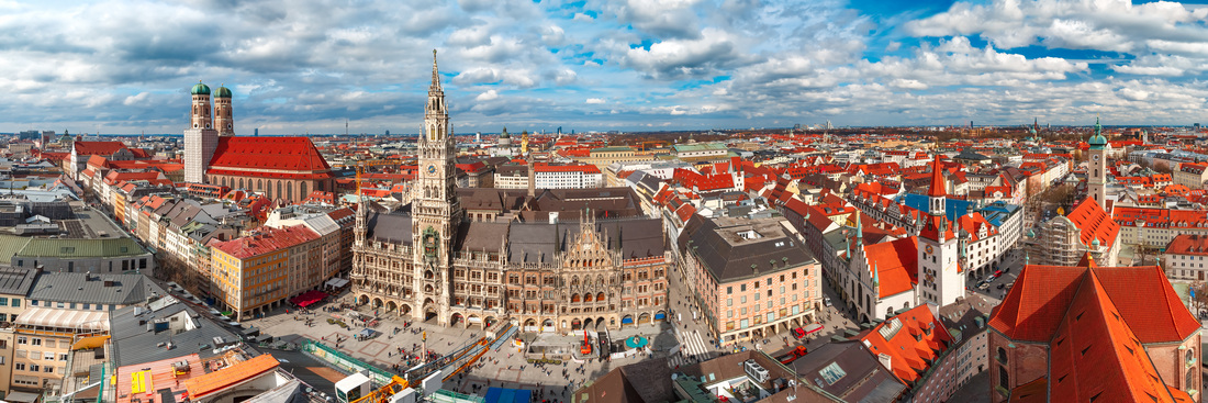 Das Bild zeigt eine Panoramaansicht der Stadt München mit Marienplatz, Rathaus und Frauenkirche.